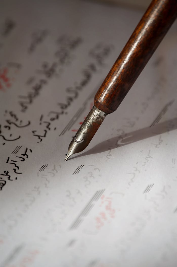 An intimate view of a vintage fountain pen poised over handwritten Arabic text.