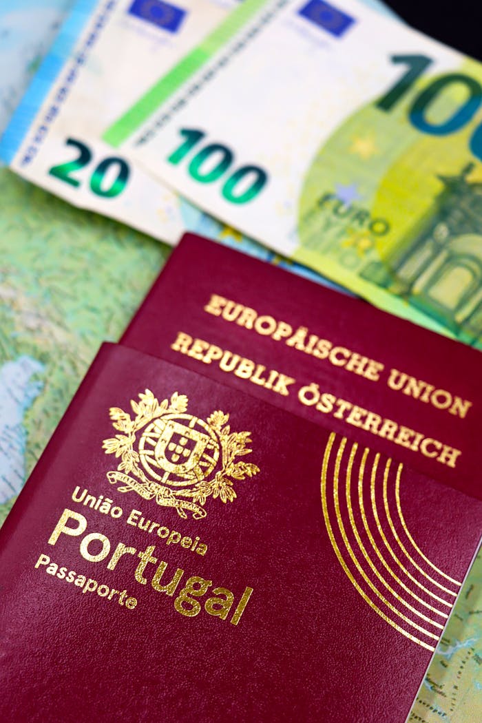 Close-up of Portuguese and Austrian passports with Euro banknotes on map.