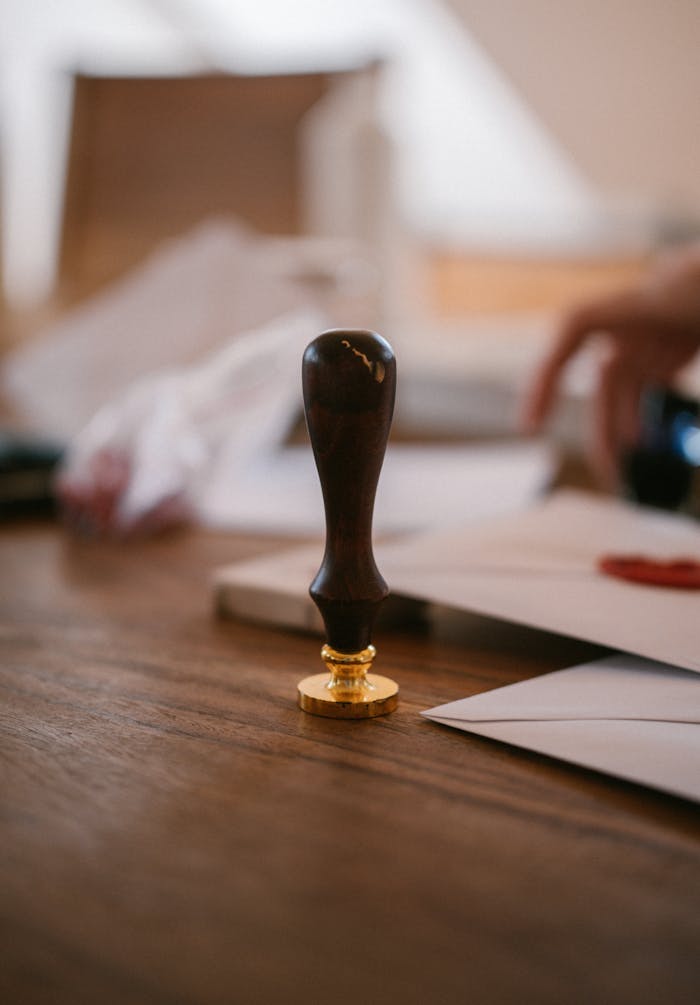 A close-up of a vintage wax seal stamp on a wooden desk with envelopes, conveying an old-world charm.