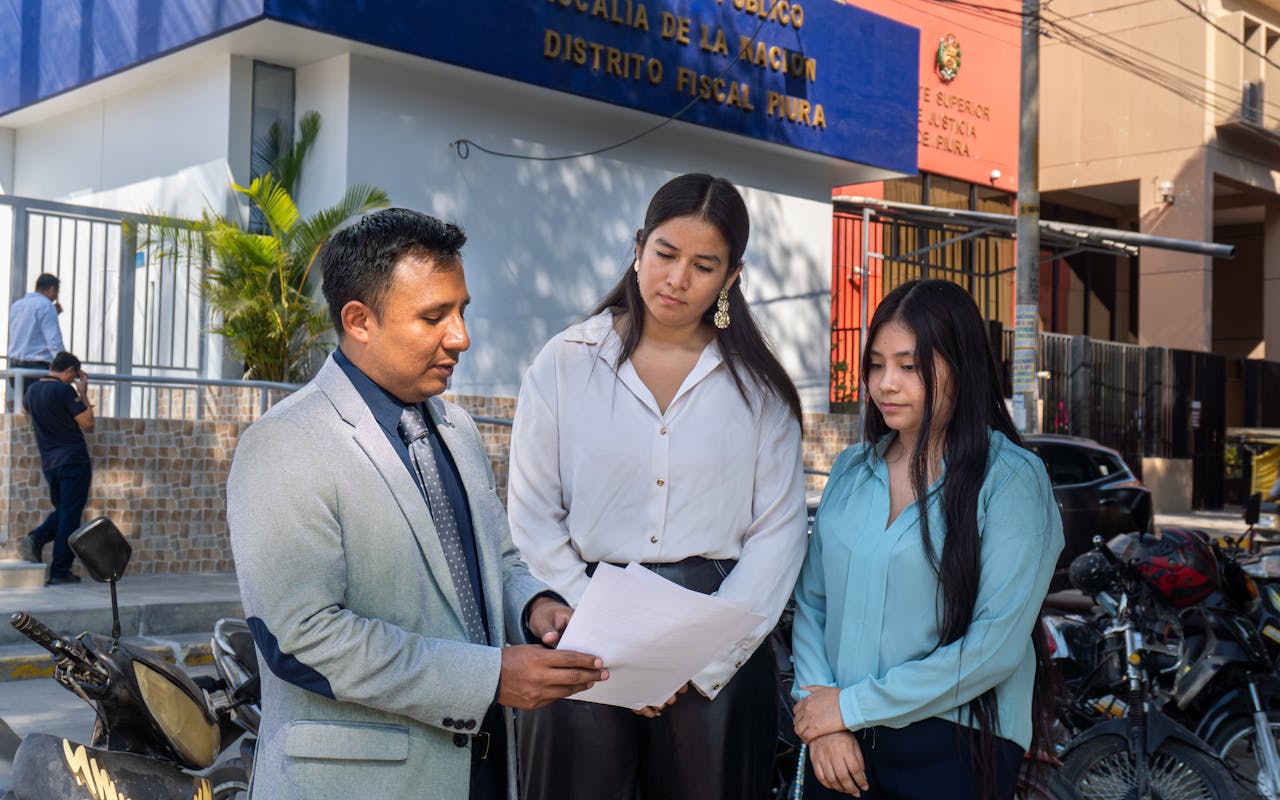 Legal consultation outside the Piura District Office, Piura, Peru. People discussing documents.