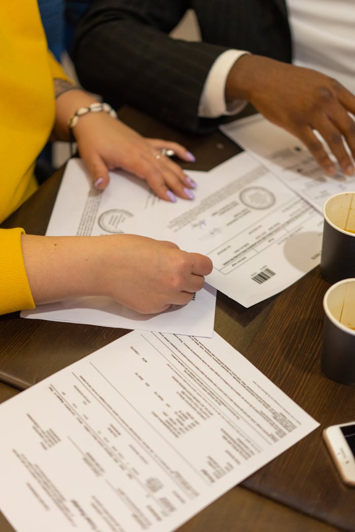 Multiracial colleagues collaborating in a business meeting, reviewing documents on a wooden table.