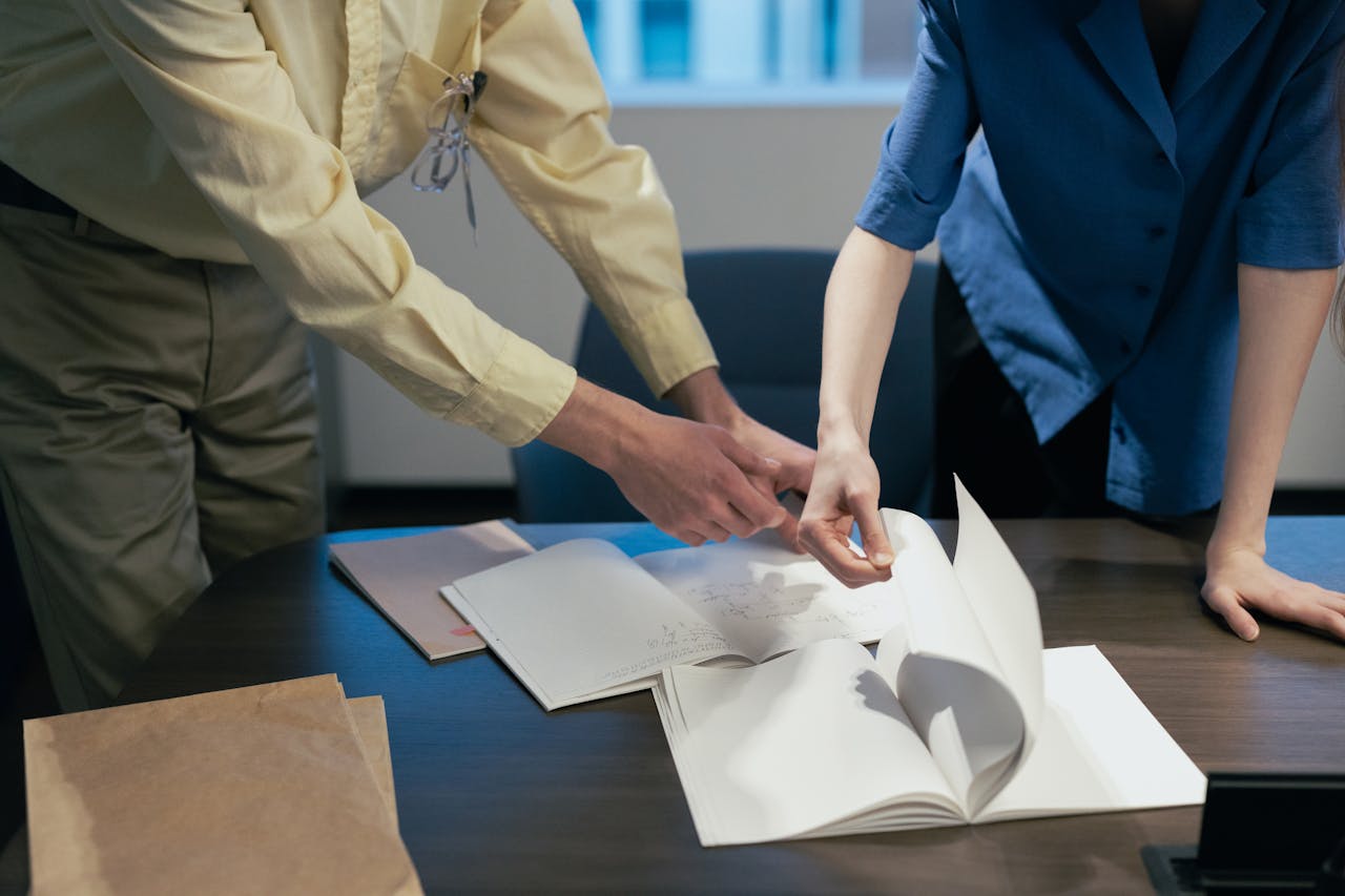 Two professionals engaged in a workplace discussion reviewing documents.